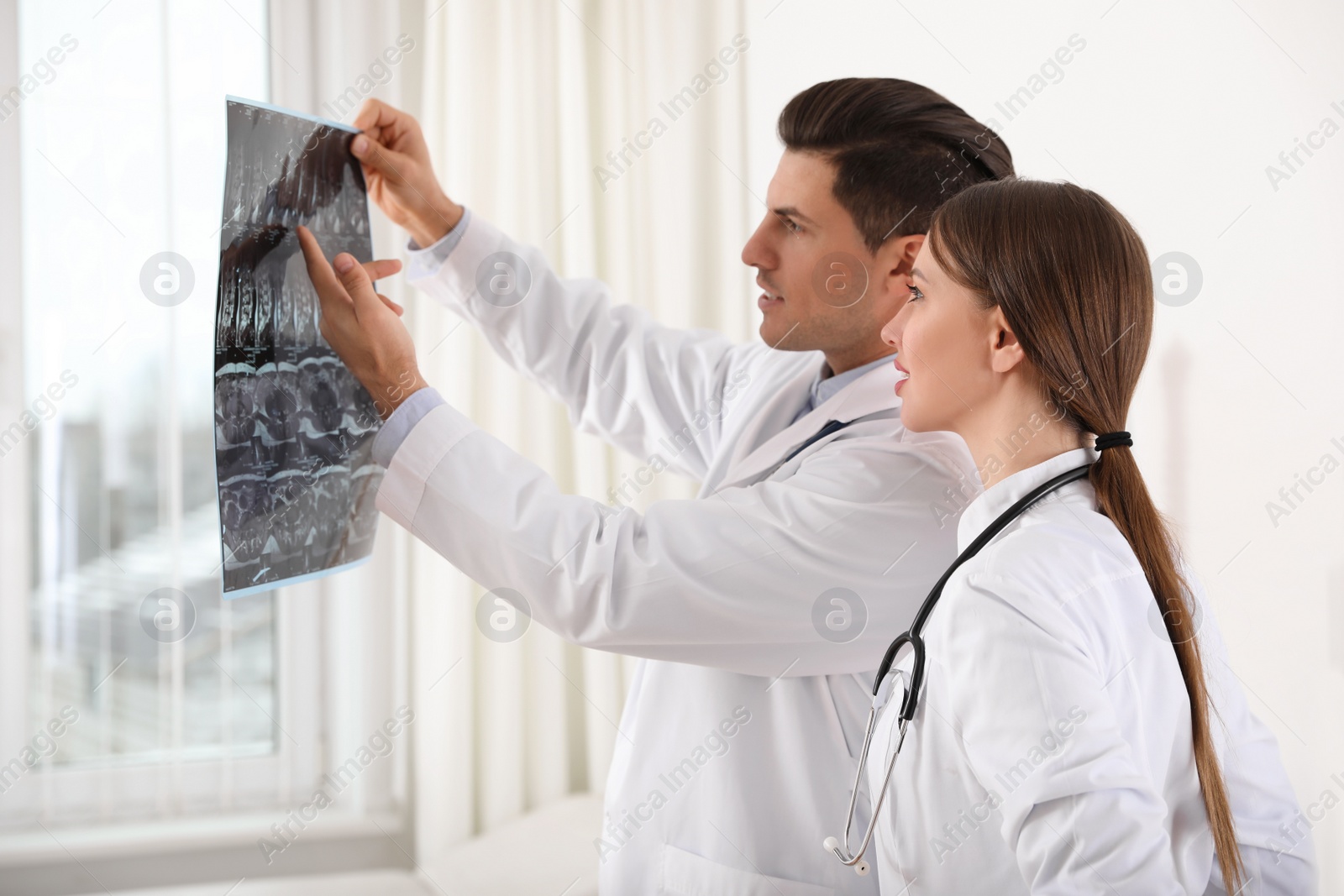 Photo of Orthopedists examining X-ray picture near window in office