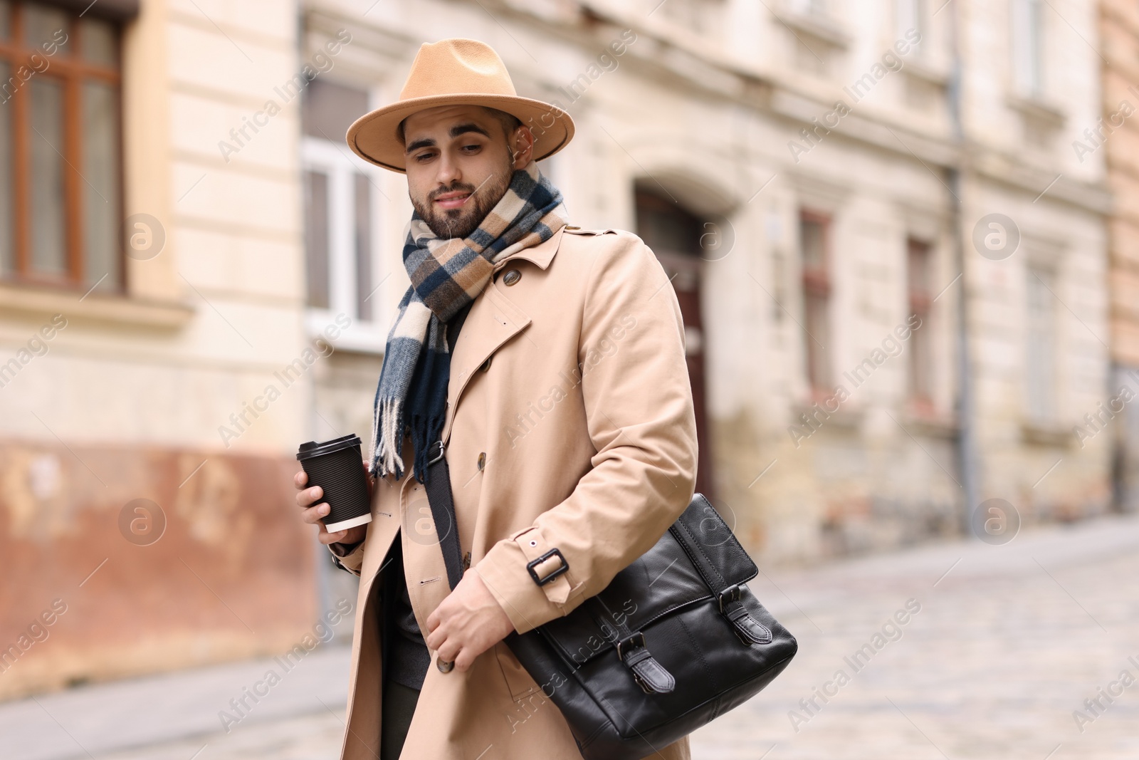 Photo of Handsome man in warm scarf with paper cup outdoors