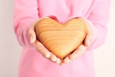 Photo of African-American woman holding wooden heart on white background, closeup