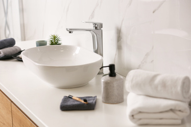 Photo of Toiletries and stylish vessel sink on light countertop in modern bathroom