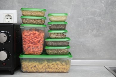 Photo of Plastic containers filled with food products on grey table in kitchen. Space for text