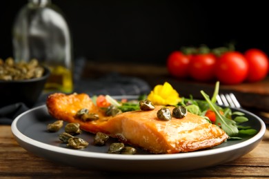 Photo of Tasty cooked salmon with capers served on wooden table, closeup