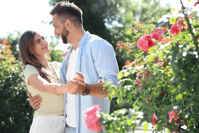 Lovely young couple dancing together in park on sunny day