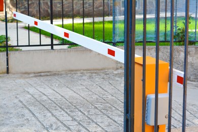 Photo of Closed boom barrier near metal fence outdoors