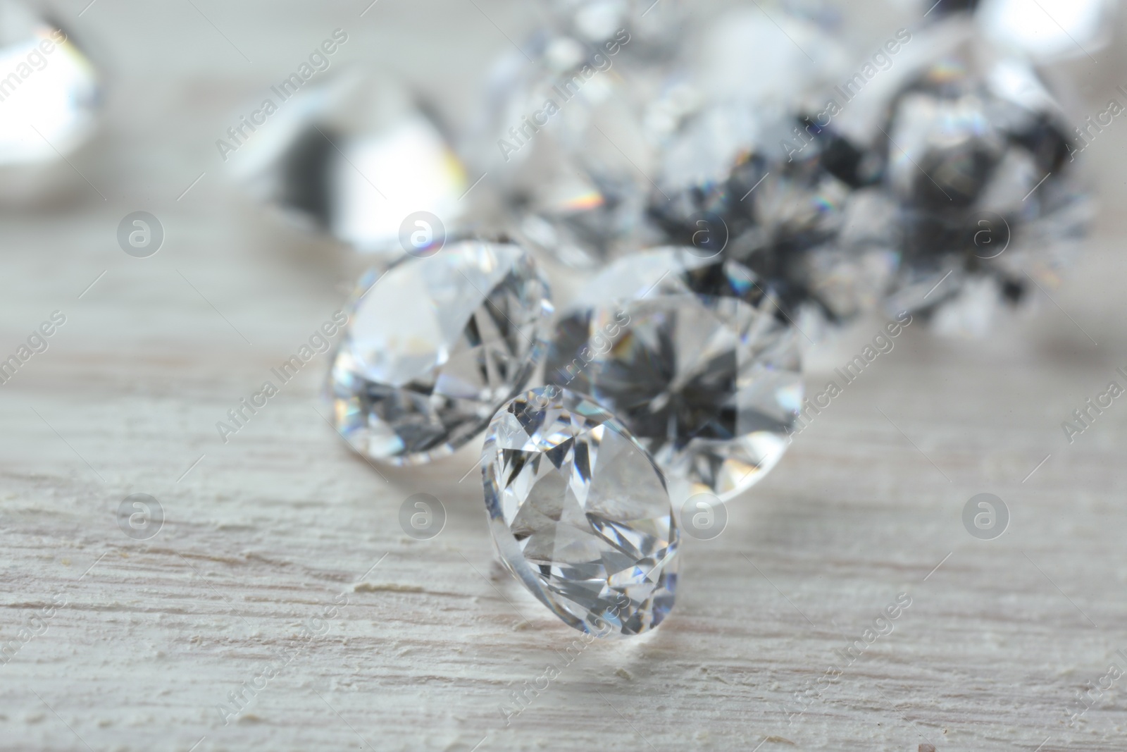 Photo of Beautiful shiny diamonds on light wooden table