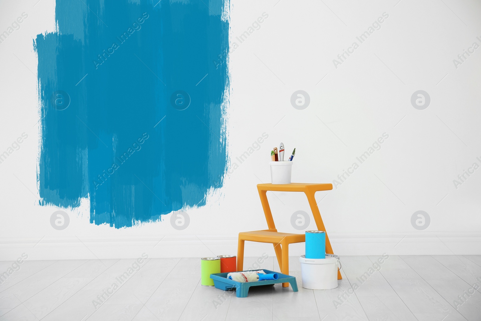 Image of Set with decorator's tools and paint on floor near white wall