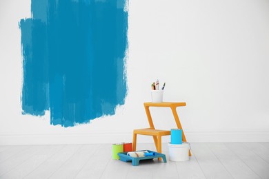 Set with decorator's tools and paint on floor near white wall