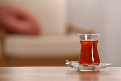 Photo of Glass with tasty Turkish tea on wooden table indoors, space for text