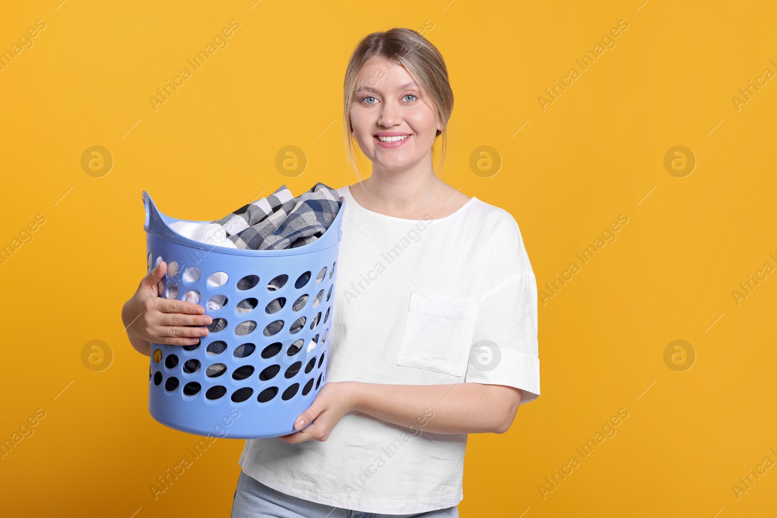 Photo of Happy woman with basket full of laundry on orange background