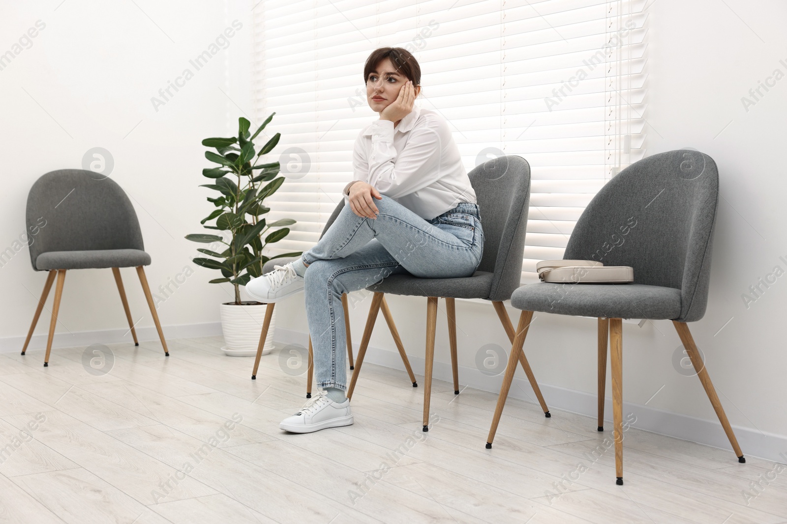 Photo of Woman sitting on chair and waiting for appointment indoors