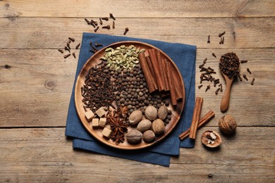 Photo of Spoon with different spices and nuts on wooden table, flat lay