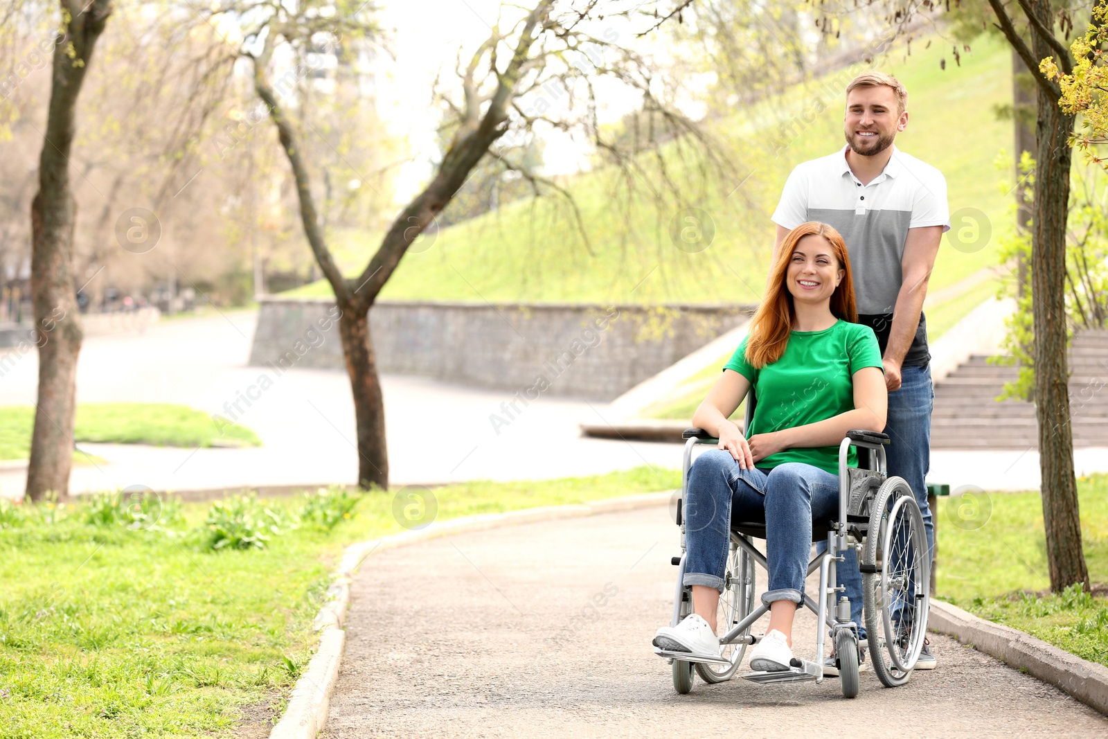Photo of Happy woman in wheelchair and young man at park on sunny day