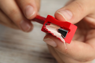 Photo of Woman sharpening pencil at wooden table, closeup