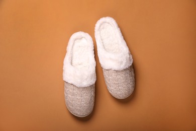 Pair of beautiful soft slippers on light brown background, top view