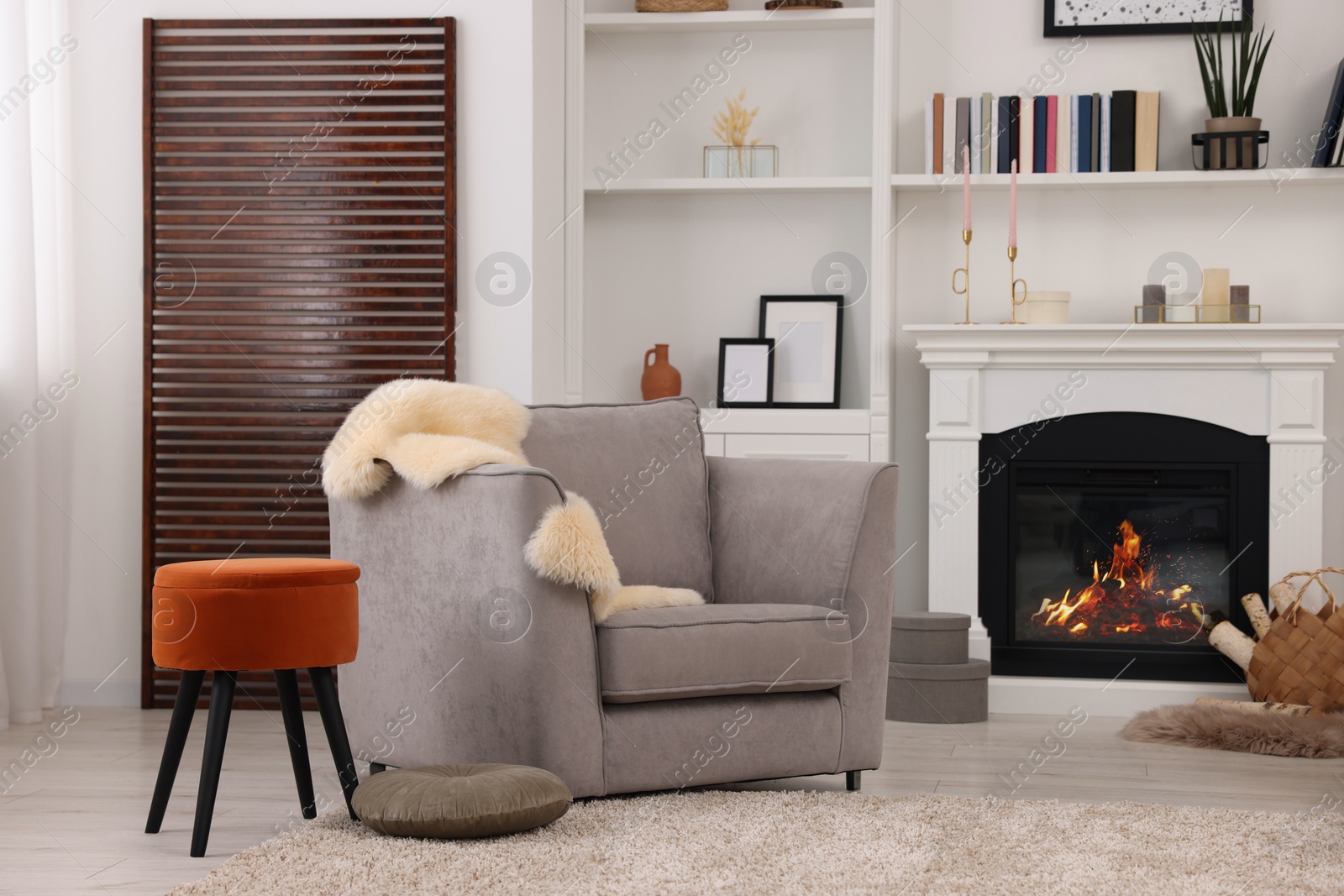 Photo of Comfortable armchair, fireplace and shelves in living room. Interior design