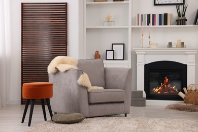 Comfortable armchair, fireplace and shelves in living room. Interior design