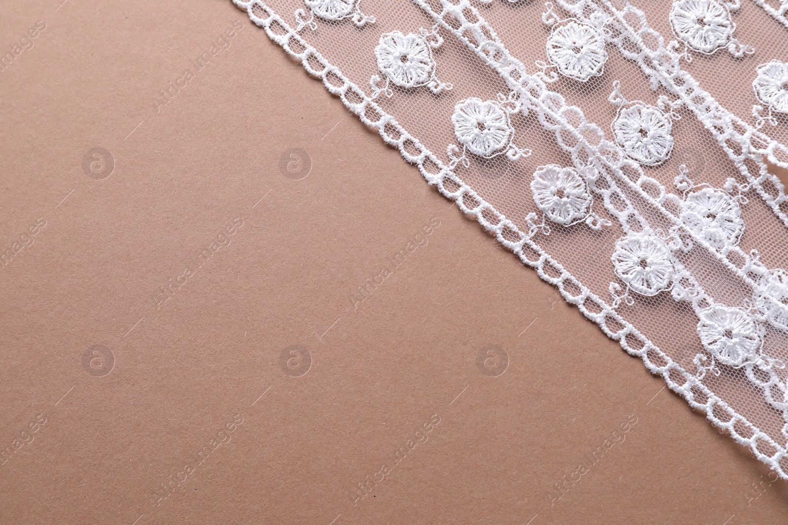 Photo of White lace on beige background, top view. Space for text