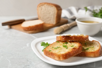 Photo of Slices of toasted bread with garlic and herb on light grey marble table