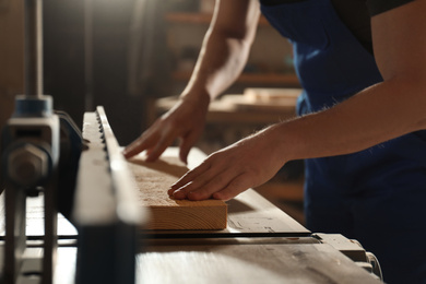 Professional carpenter working with wood in shop, closeup