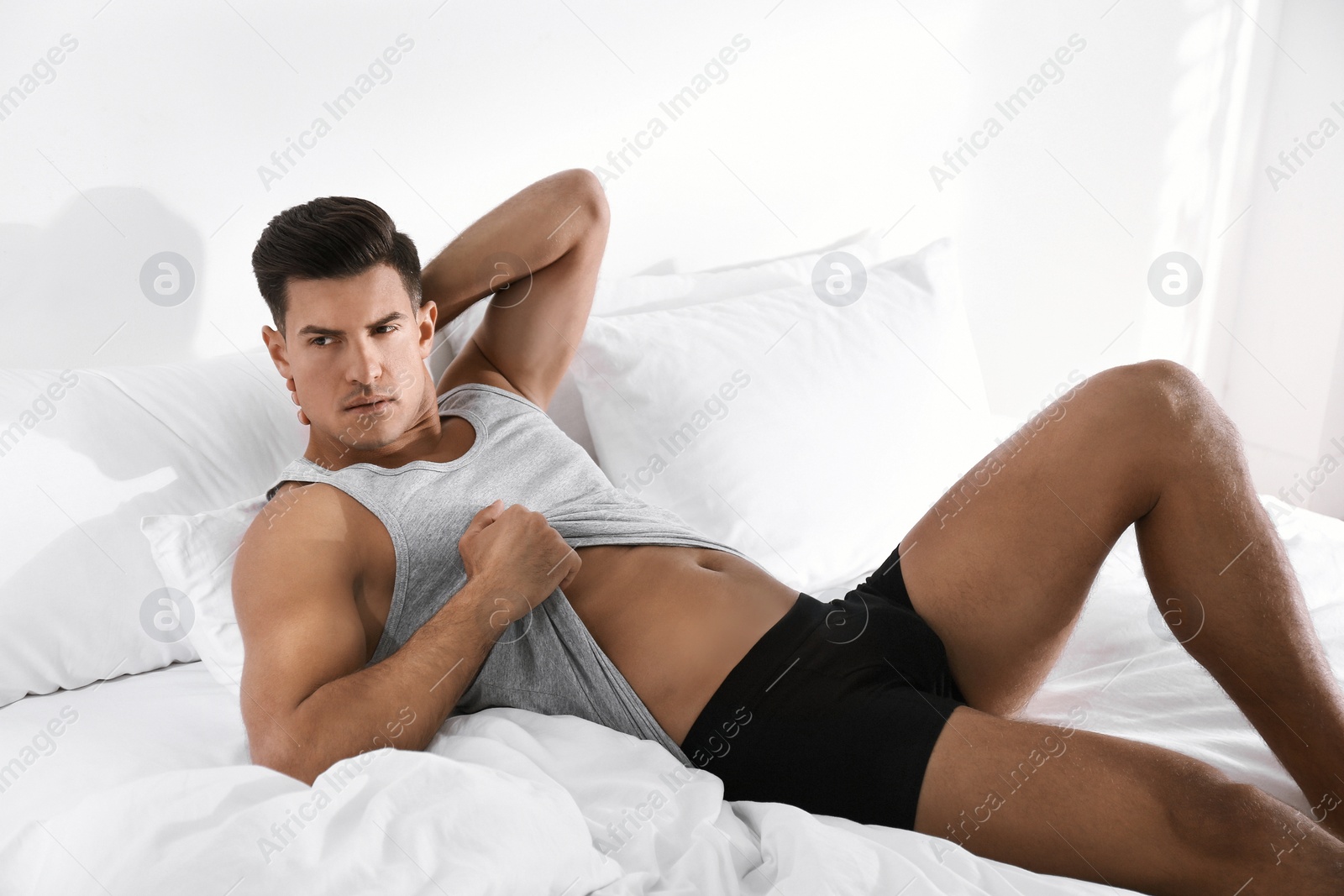 Photo of Handsome man in underwear on bed indoors