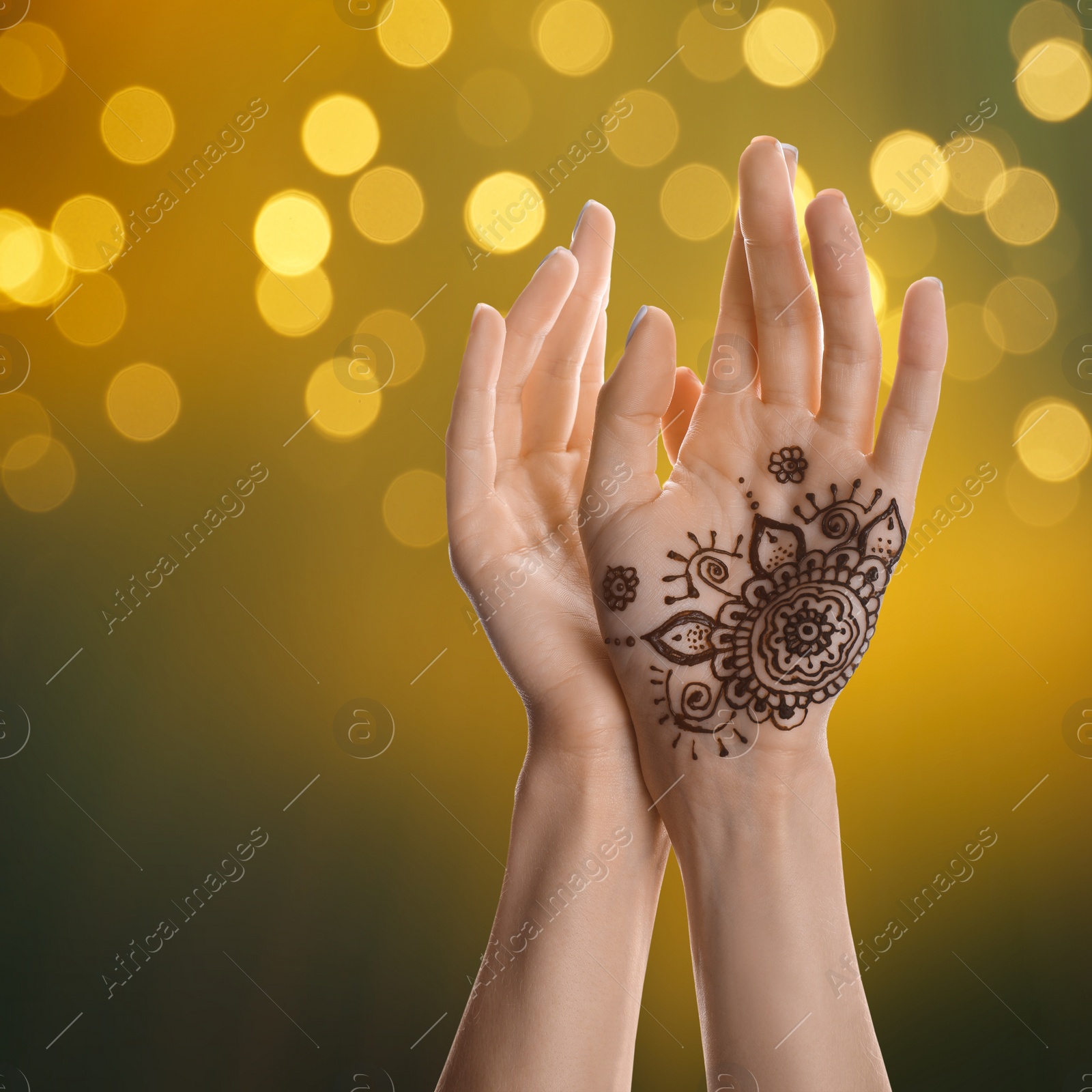 Image of Woman with henna tattoo on palm against blurred lights, bokeh effect