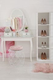 Photo of Stylish dressing room interior with shoes on shelving unit and table