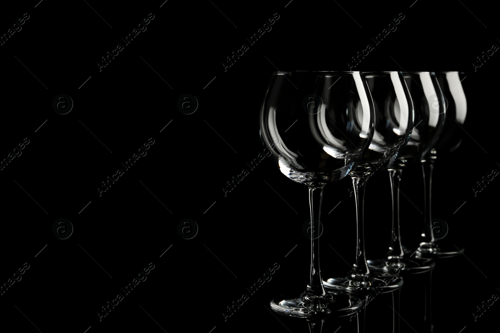 Photo of Set of empty wine glasses on black background. Space for text