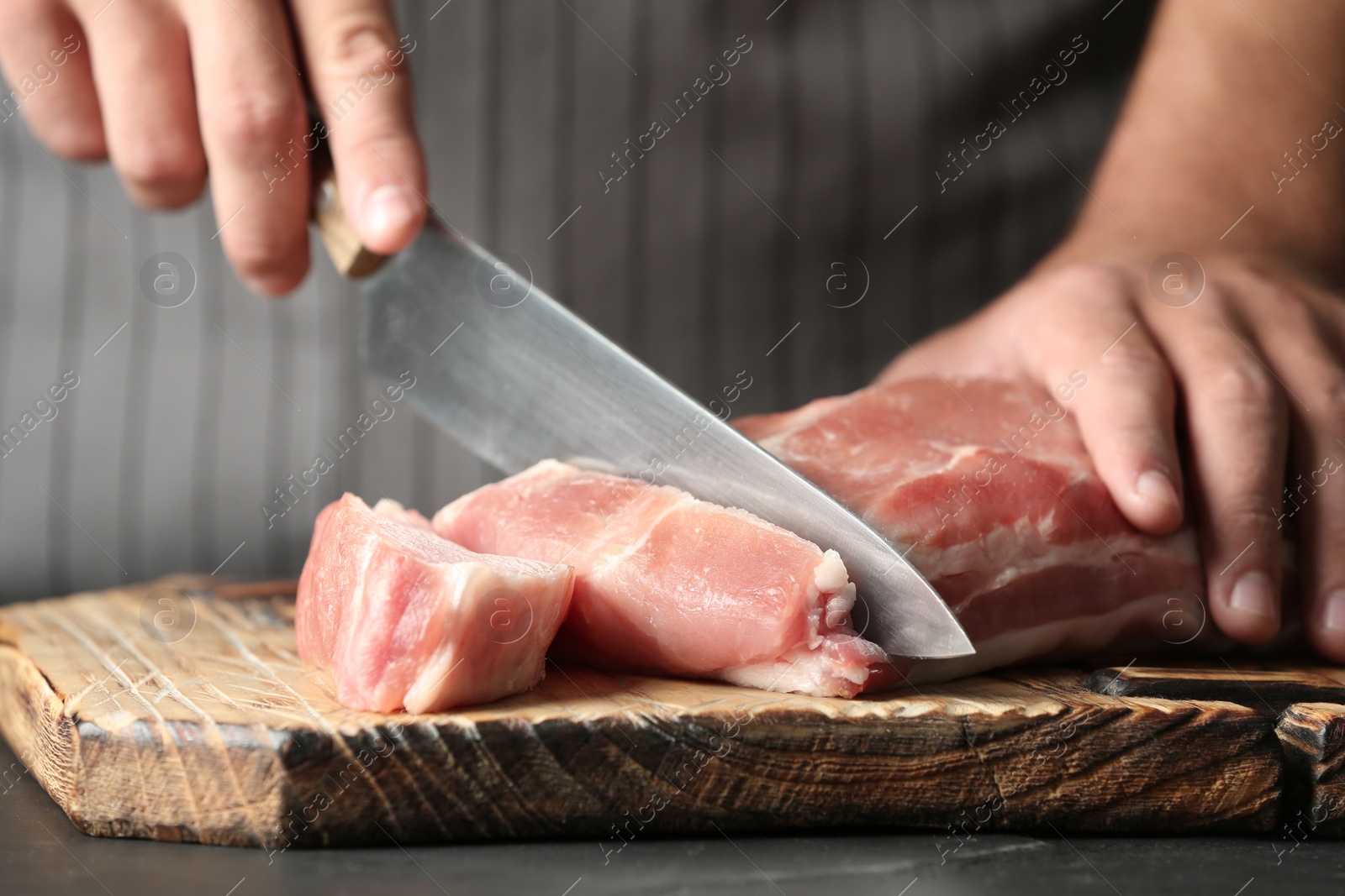 Photo of Man cutting fresh raw meat on table, closeup