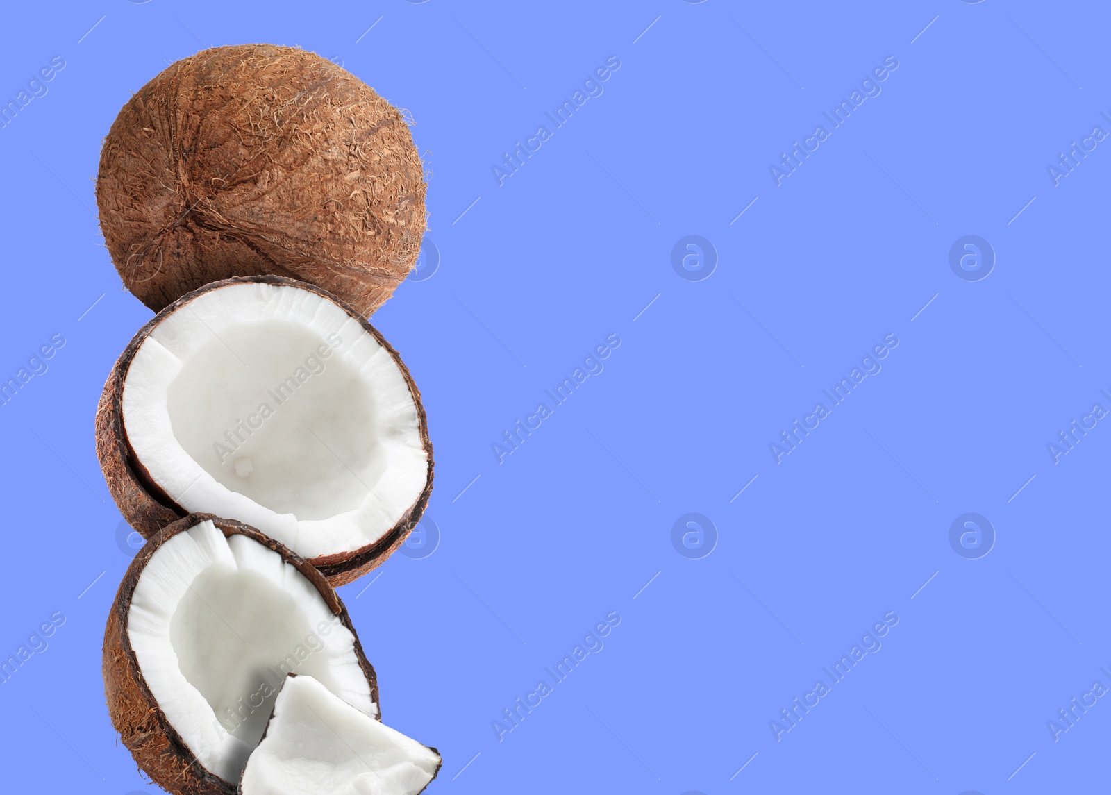 Image of Stack of fresh coconuts on pale blue background. Space for text