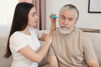 Photo of Young woman dripping medication into man's ear at home