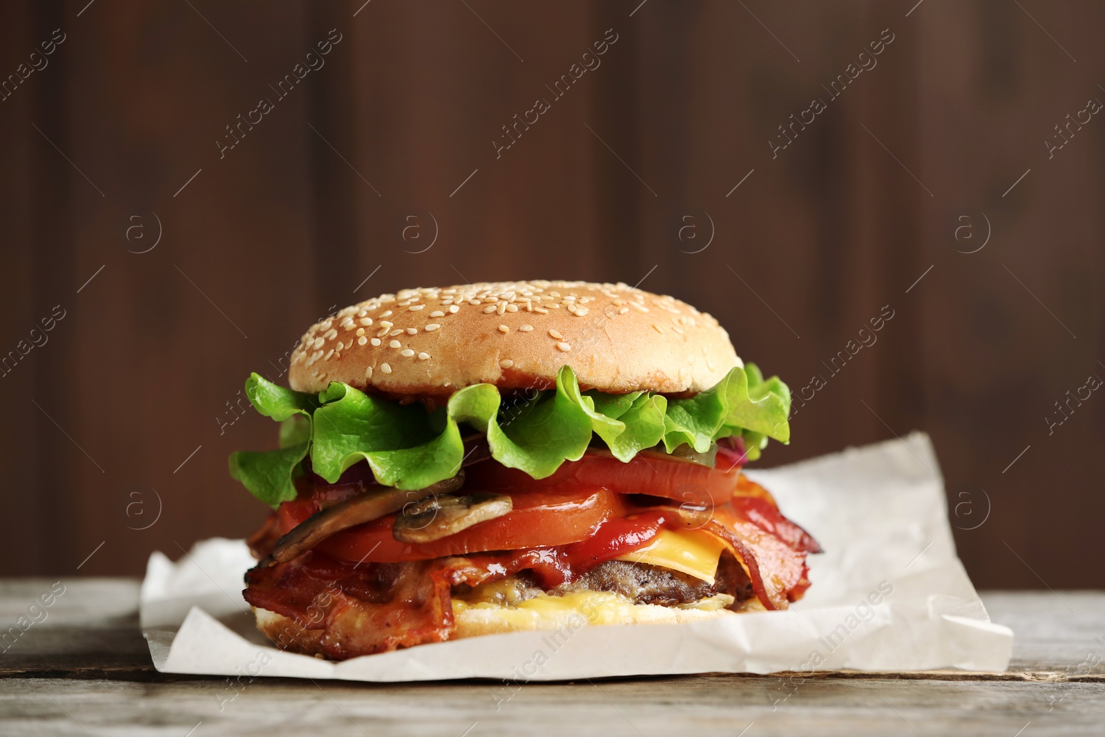 Photo of Tasty burger with bacon on wooden table