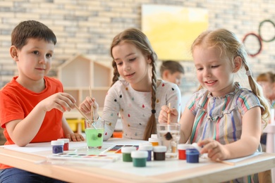 Photo of Cute little children painting at table indoors. Learning by playing