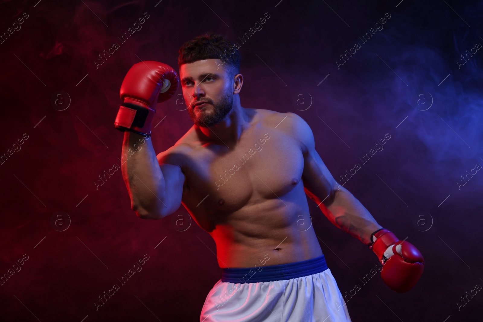 Photo of Man wearing boxing gloves fighting on dark background