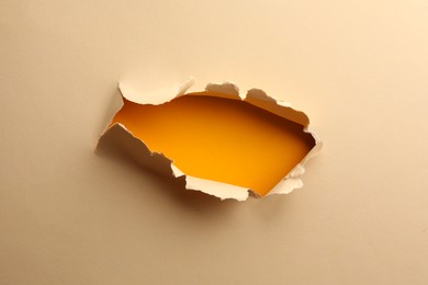 Hole in light beige paper on yellow background