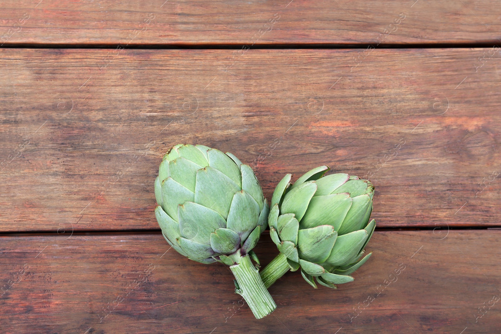 Photo of Fresh raw artichokes on wooden table, flat lay