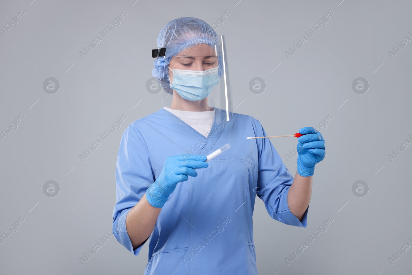 Photo of Laboratory testing. Doctor with cotton swab and tube on light grey background