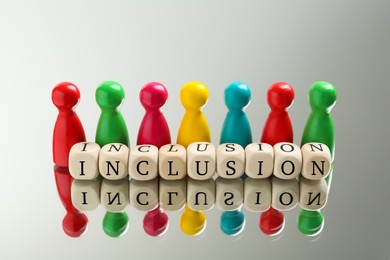 Colorful pawns and wooden cubes with word Inclusion on white background