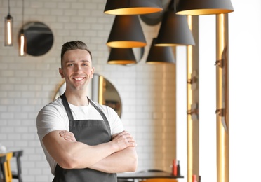 Photo of Portrait of young waiter in uniform at cafe