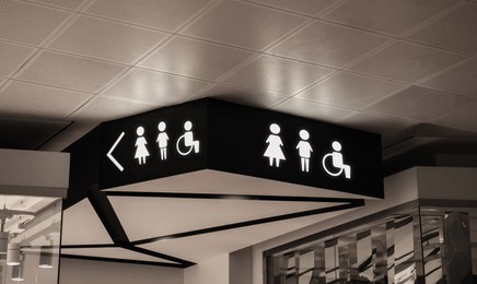 Symbols on black sign in mall near public toilet