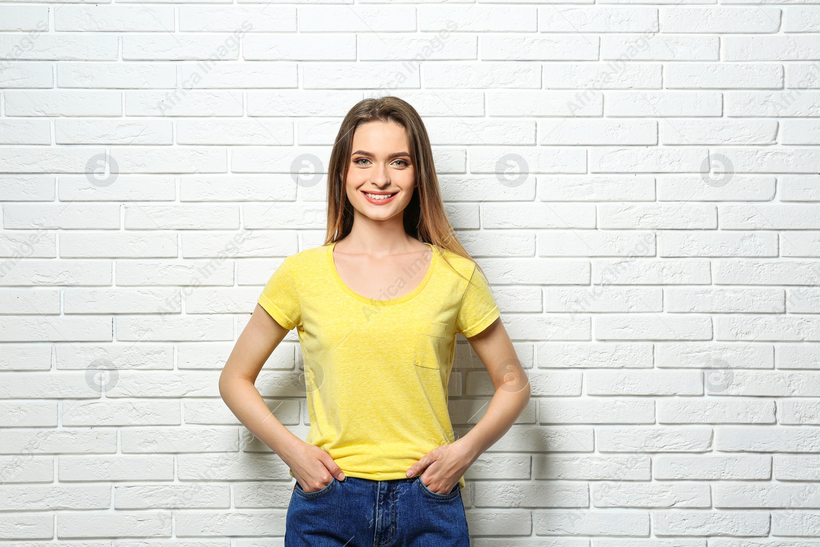Photo of Young woman wearing blank t-shirt near white brick wall. Mockup for design