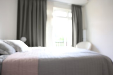 Photo of Blurred view of large bed near window in room