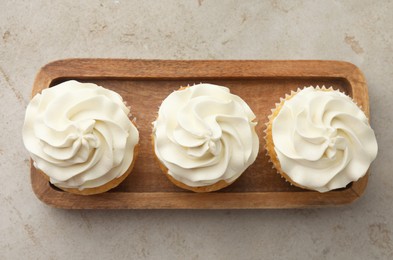 Photo of Tasty cupcakes with vanilla cream on light grey table, top view