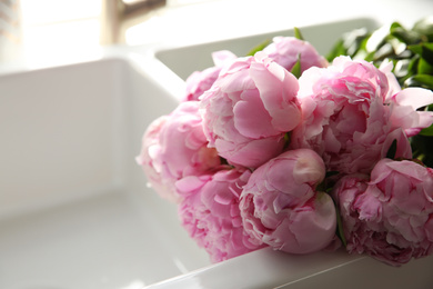 Photo of Bouquet of beautiful pink peonies in kitchen sink, closeup