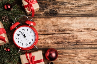 Flat lay composition with Christmas gifts and alarm clock on wooden table, space for text. Boxing day