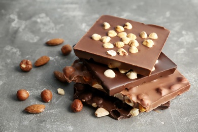 Photo of Delicious milk and dark chocolate bars with nuts on table