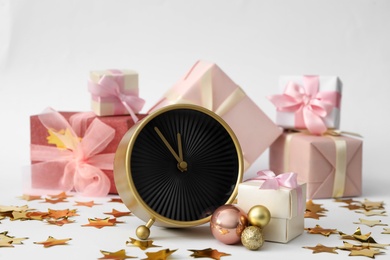 Alarm clock with gifts and festive decor on white background. New Year countdown