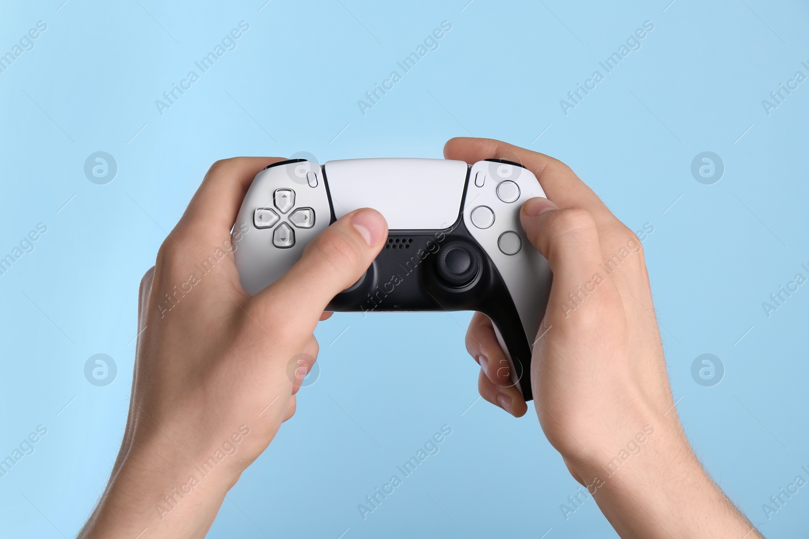 Photo of Man using wireless game controller on light blue background, closeup