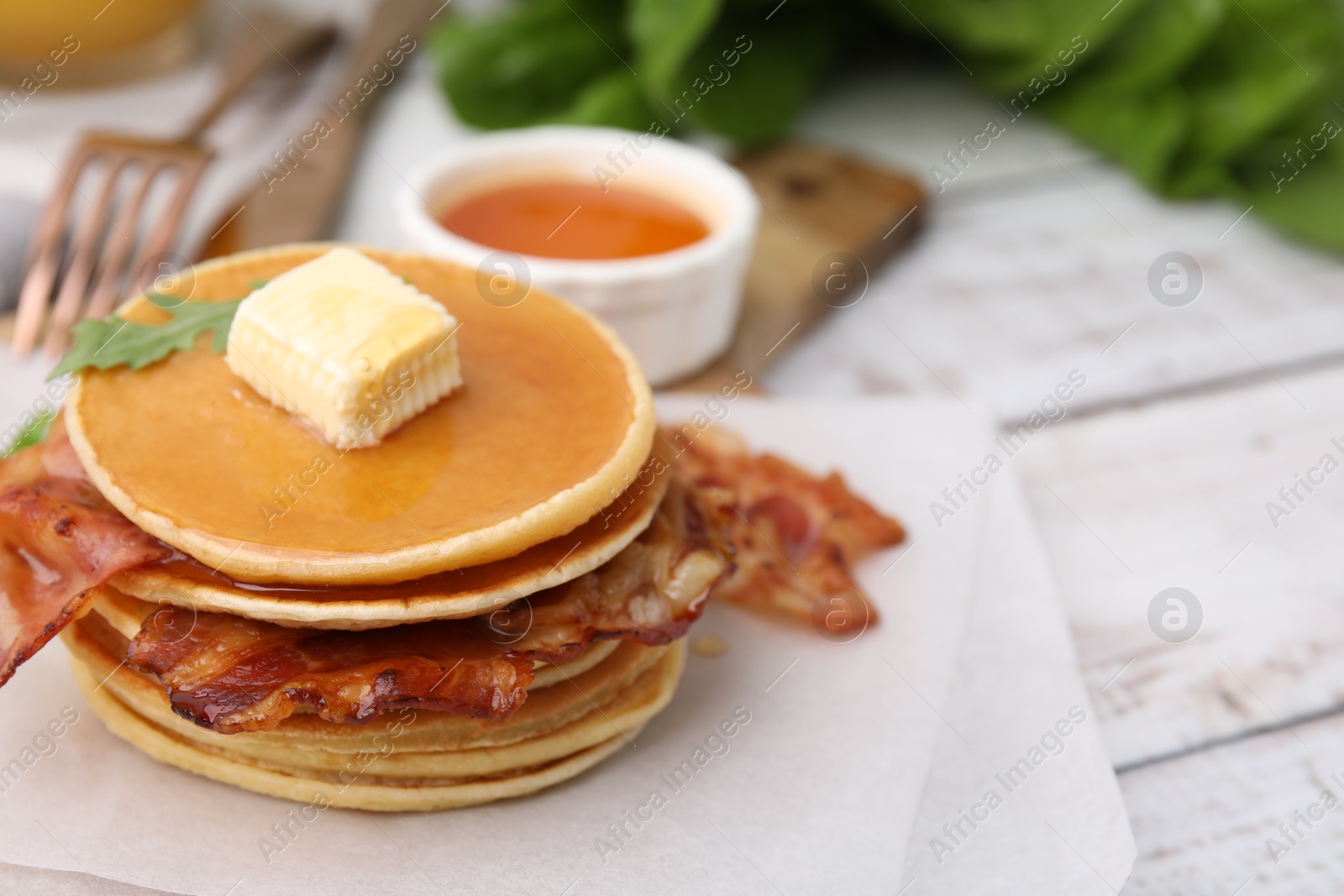 Photo of Delicious pancakes with bacon, butter and honey on table, closeup. Space for text