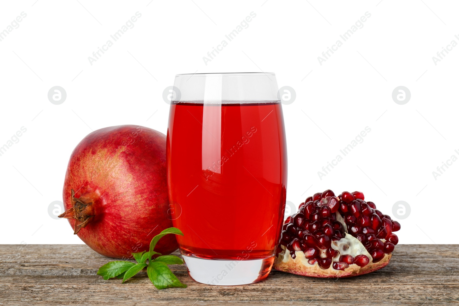 Photo of Refreshing pomegranate juice in glass, leaves and fruits on wooden table against white background