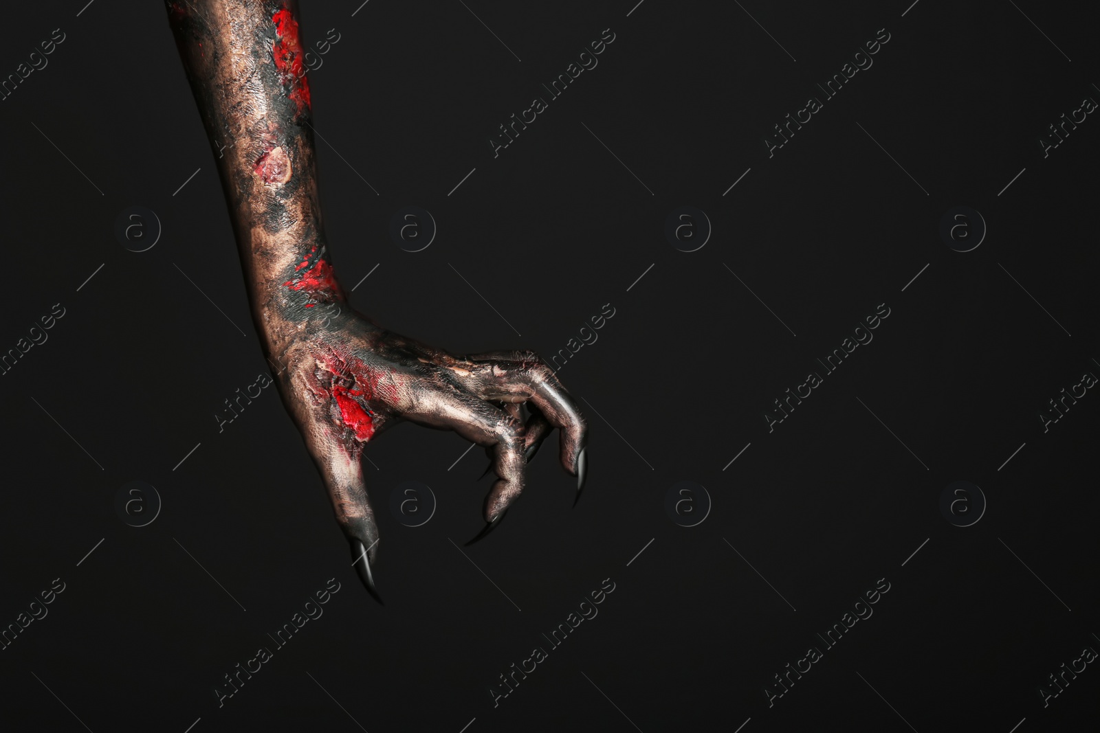 Photo of Scary monster on black background, closeup of hand with space for text. Halloween character